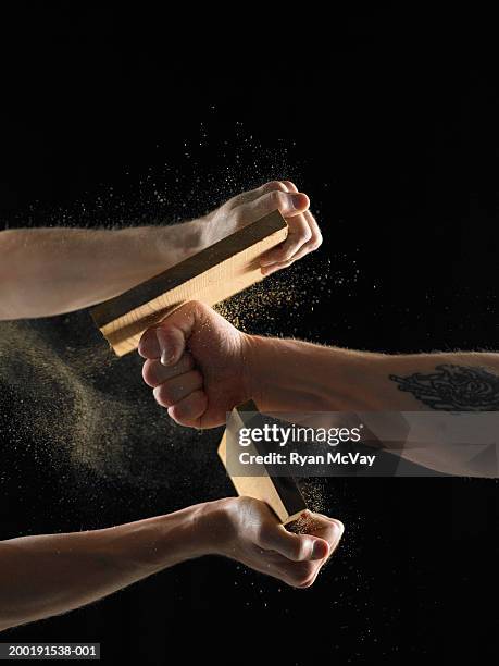 two men, one holding plank, one breaking plank with fist, close-up - karate stock pictures, royalty-free photos & images