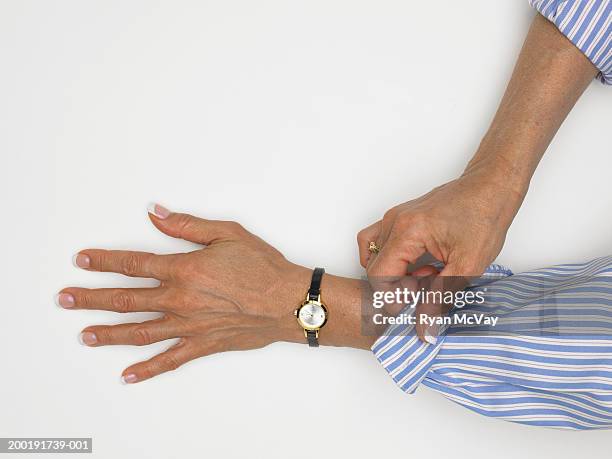 mature woman folding cuff of shirt, close-up of hands - hochgekrempelte ärmel stock-fotos und bilder