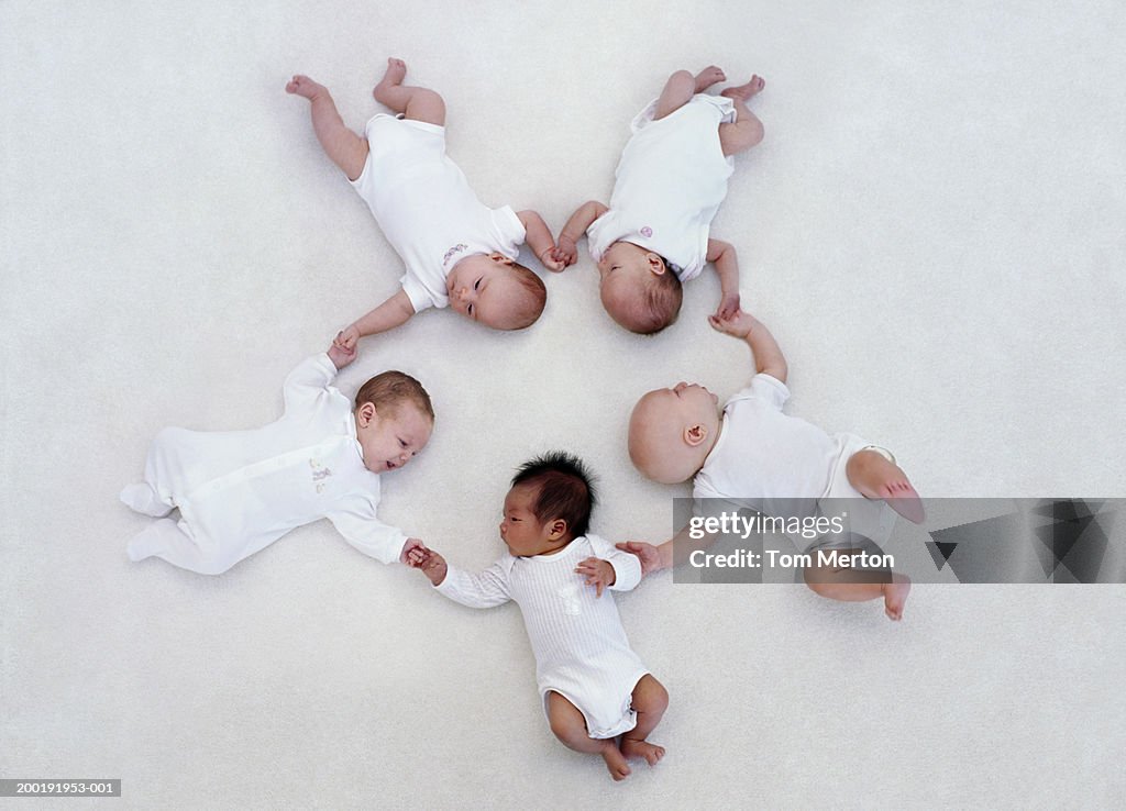 Five babies (0-3 months) lying on floor in circle (Digital Composite)
