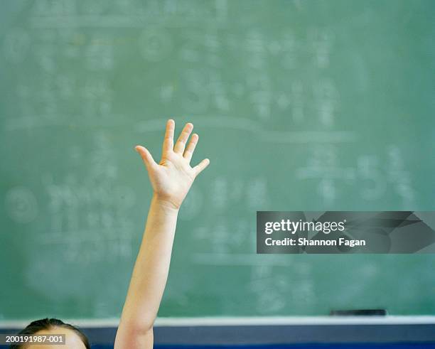 female student (12-14) raising hand in classroom, close-up - schultafel stock-fotos und bilder