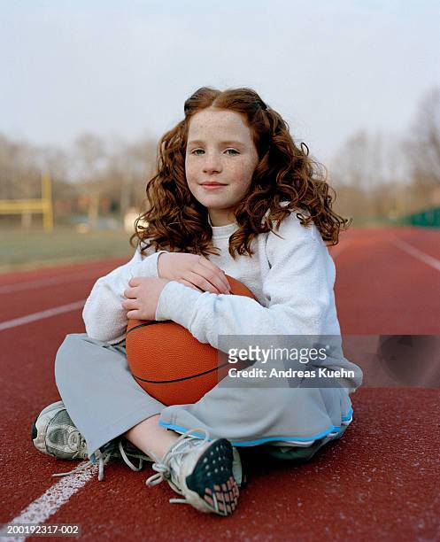 girl (8-10) with basketball sitting on track field, portrait - 8 ball stock-fotos und bilder