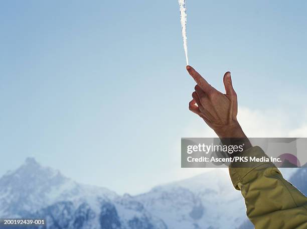 mature woman balancing icicle on finger tip, close-up - 0703ef stock pictures, royalty-free photos & images