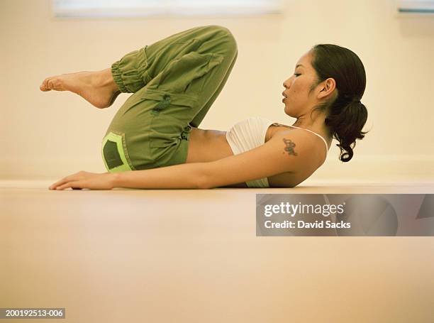 young woman doing floor exercise, side view - lying on back stock pictures, royalty-free photos & images