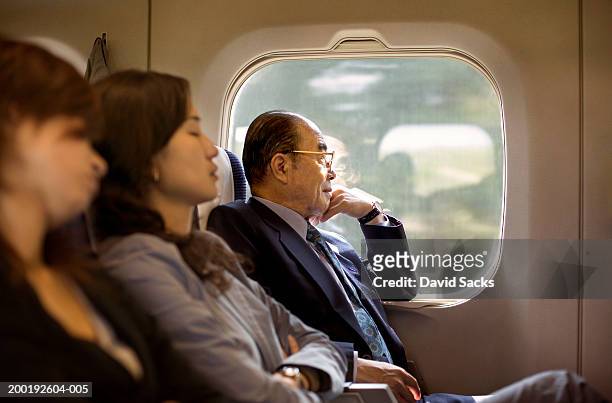 Businesspeople riding on train, side view (focus on senior man)