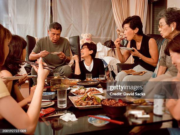 multi generational family dining in living room - asians eating stock pictures, royalty-free photos & images