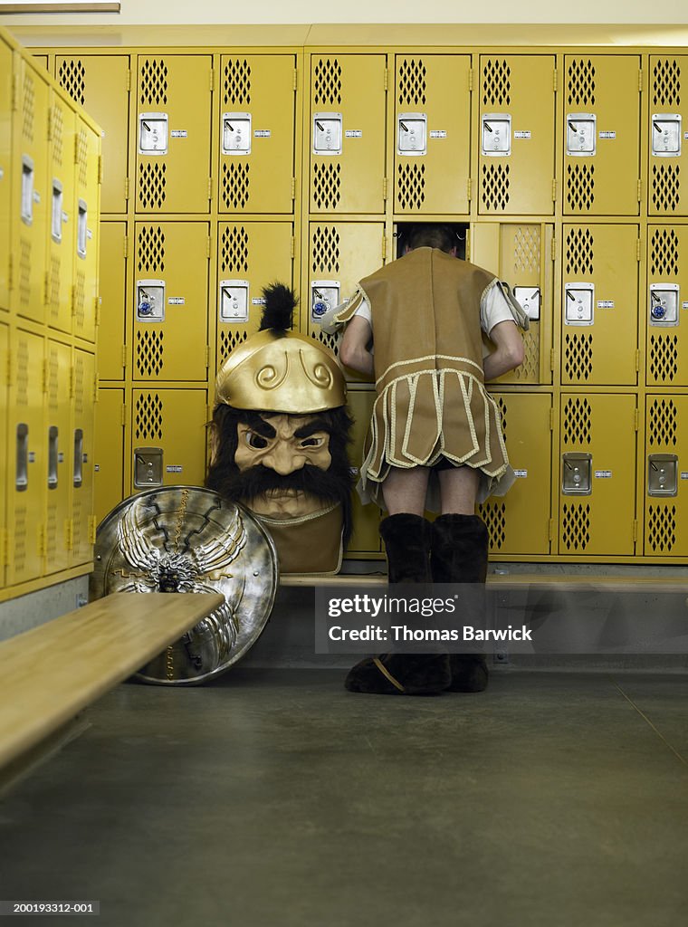 Teenage boy (15-17) in mascot costume, head in locker, rear view