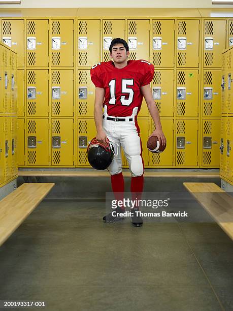 teenage boy (16-18) dressed for football,  standing in locker room - american football uniform stock pictures, royalty-free photos & images
