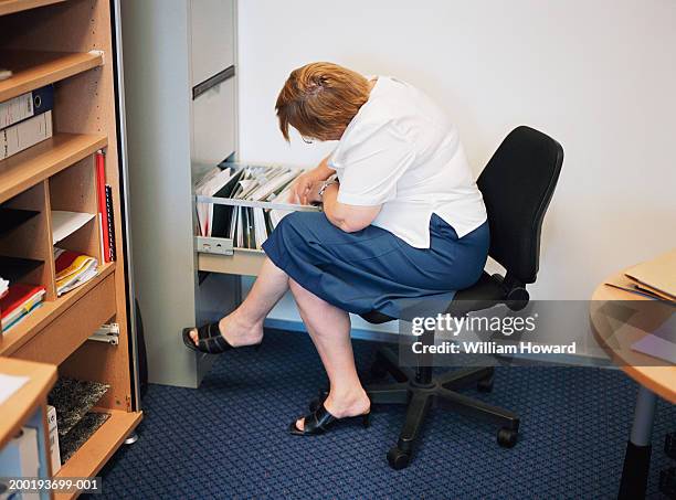 mature businesswoman looking in files - sandal stock pictures, royalty-free photos & images