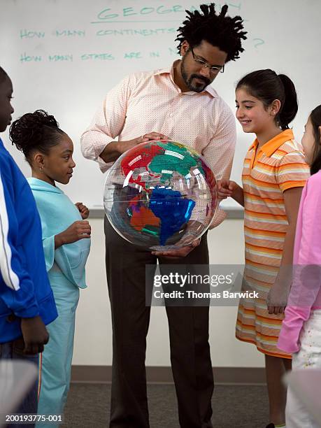 teacher showing students (8-10) globe - physical geography stock-fotos und bilder