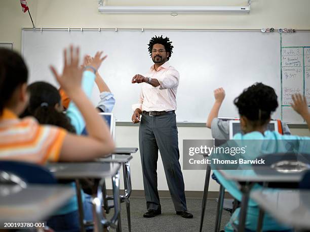male teacher standing before students (8-10) with hands raised - male teacher in a classroom stock-fotos und bilder