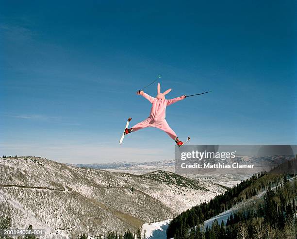 person wearing pink bunny suit ski jumping, rear view - exzentrisch stock-fotos und bilder