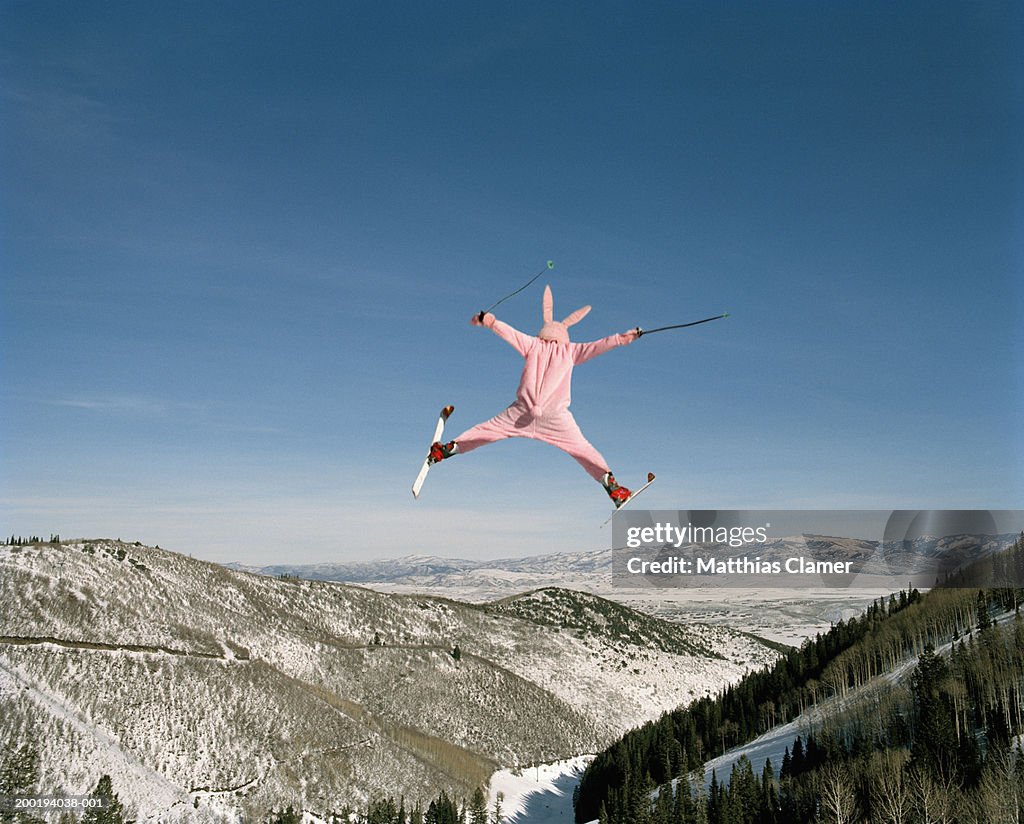 Person wearing pink bunny suit ski jumping, rear view