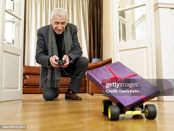 senior man driving remote control car carrying gift-wrapped present - remote controlled car fotografías e imágenes de stock