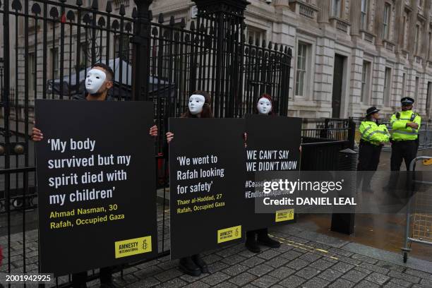 Activists from Amnesty International hold placards with statements made by civilians living in Rafah, in Gaza, during a silent vigil outside the...