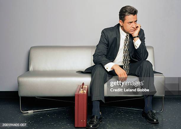 mature businessman sitting on couch, hand to chin - job interview nervous stock pictures, royalty-free photos & images