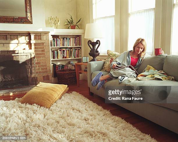 woman relaxing on sofa, reading magazine - ラグ ストックフォトと画像