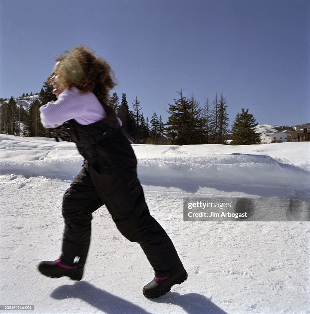 Girl (6-8) walking in snow field, side view