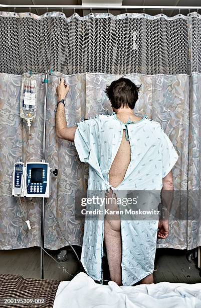 mature man in examination gown with iv drip, rear view - hospital gown stock photos et images de collection