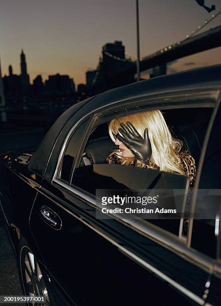woman sitting in limousine, shielding face from camera, dusk - 2004 fotografías e imágenes de stock