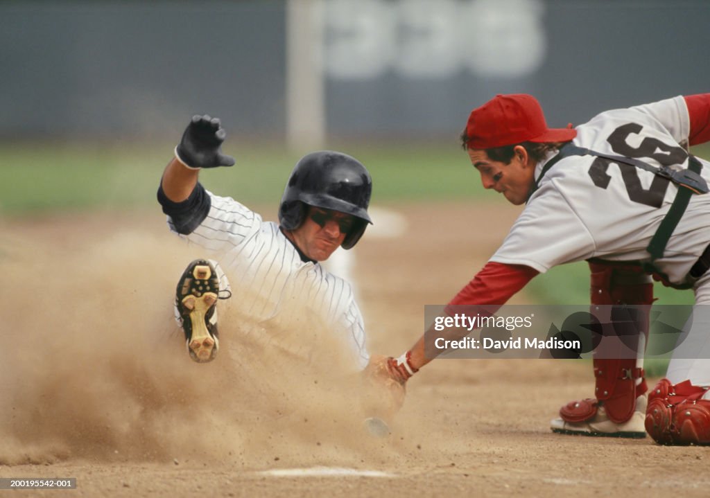 Baseball player sliding into home plate, being tagged by catcher