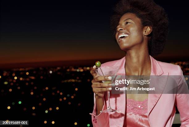 young woman on balcony holding drink, smiling, night - pink drink stock pictures, royalty-free photos & images