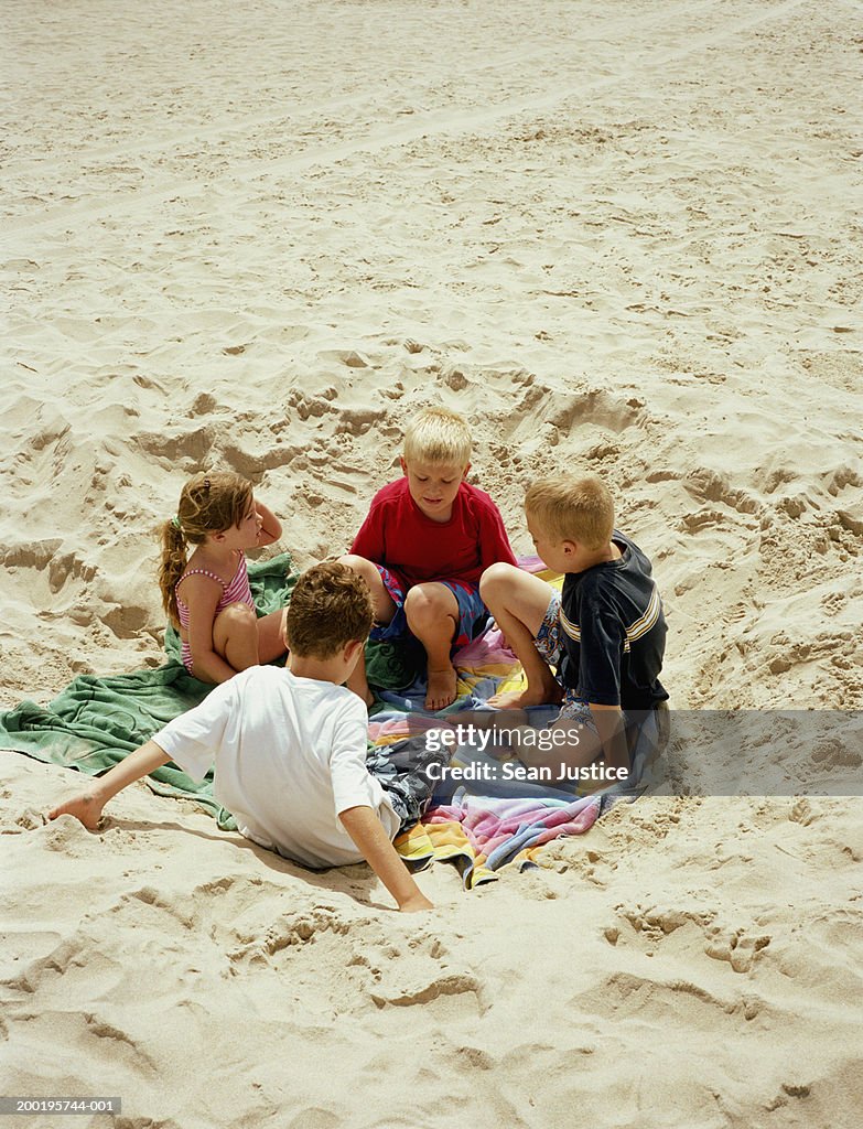 Children (4-10) sitting on towels on beach