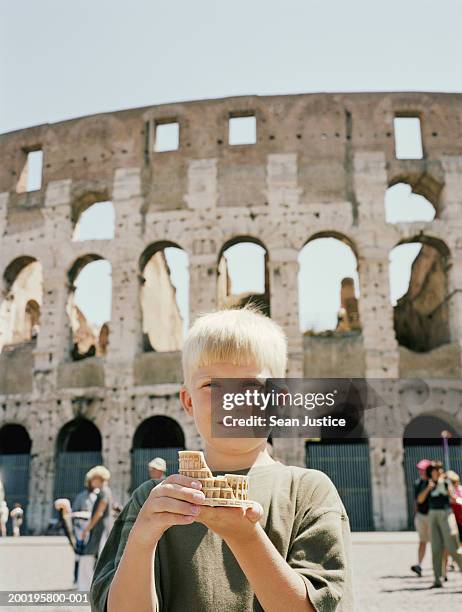 rome, italy boy (8-10) holding statue of coliseum - souvenir stockfoto's en -beelden