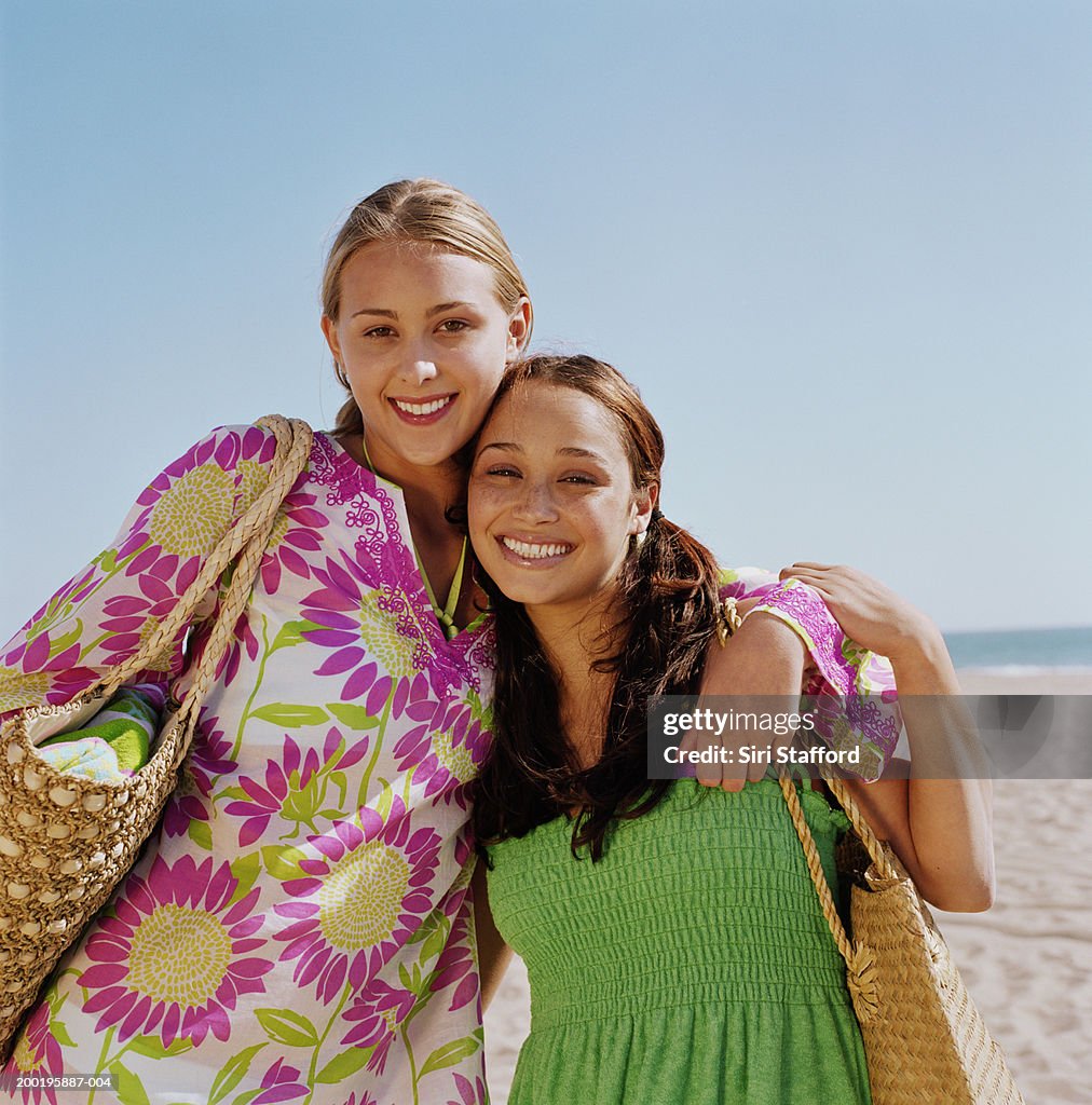 Two young women at beach, hugging, portrait