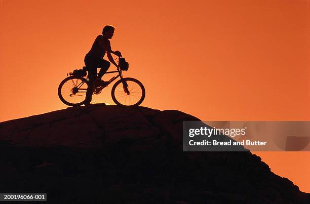 silhouette of man on mountain bicycle, side view, sunset - 思い切って飛び込む ストックフォトと画像