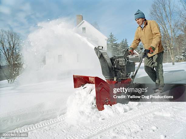 mature man using snowblower outside home, winter - snow blower stock pictures, royalty-free photos & images