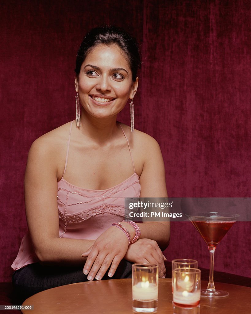 Young woman at table looking away, smiling