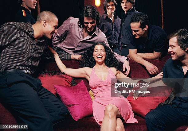 young woman on sofa in nightclub men looking at her, laughing - female with group of males stock pictures, royalty-free photos & images