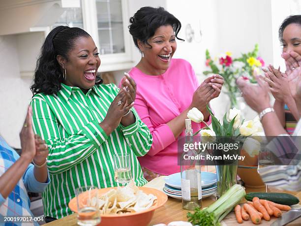 five mature women standing in kitchen, laughing, clapping hands - green blouse stock pictures, royalty-free photos & images