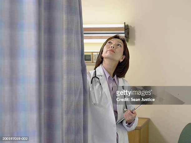 female doctor closing curtain around patient's bed - closing curtains stock pictures, royalty-free photos & images