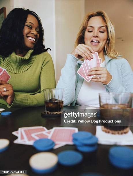 two women playing cards, smiling - avond thuis stockfoto's en -beelden