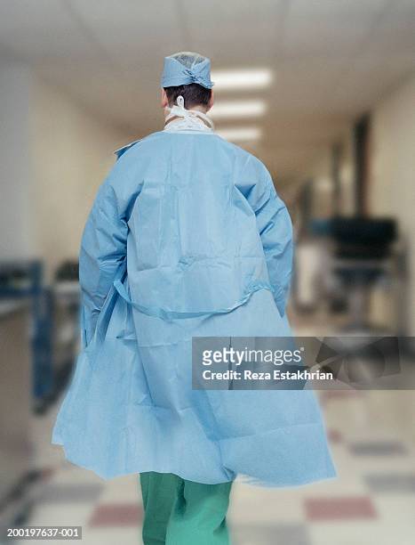 Surgeon wearing scrubs, walking down hospital corridor, rear view