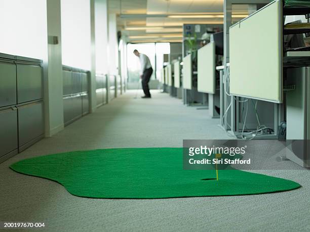businessman playing miniature golf in office, focus on hole - minigolf foto e immagini stock