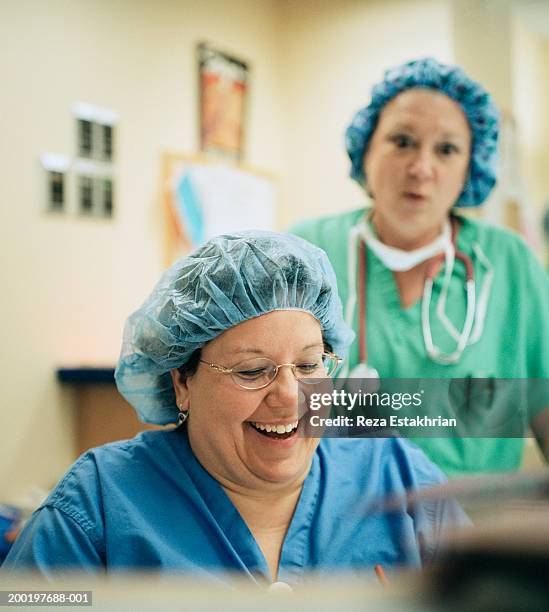 two nurses wearing scrubs (focus on nurse laughing) - nursing scrubs stock pictures, royalty-free photos & images