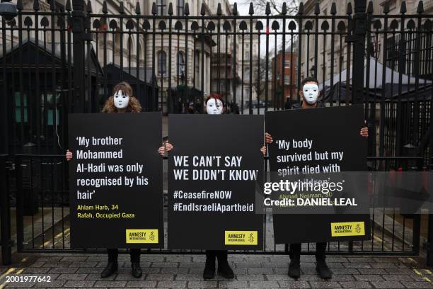 Activists from Amnesty International hold placards with statements made by civilians living in Rafah, in Gaza, during a silent vigil outside the...