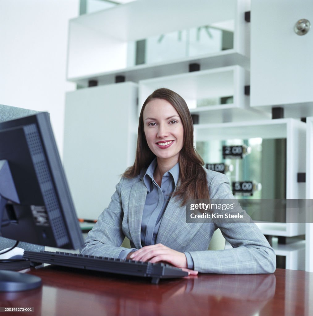 Young Woman Sitting Behind Desk With Computer Smiling Portrait High-Res ...