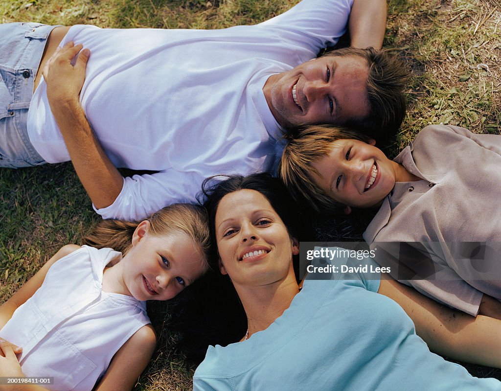 Parents and children (6-9) lying on grass, portrait, overhead view