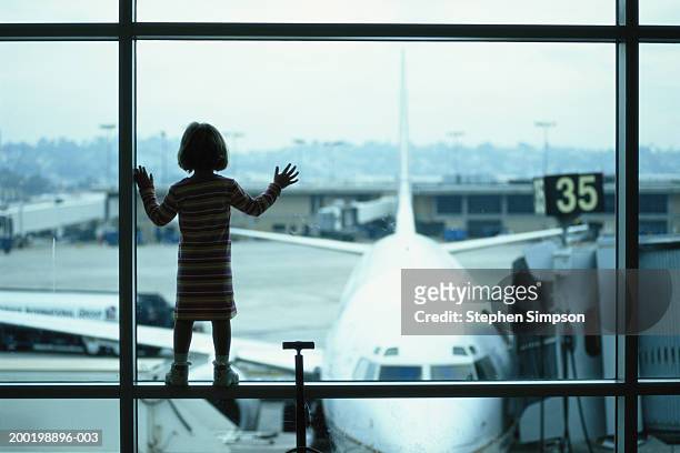 girl (3-5) looking out airport window at airplane, rear view - valise soleil stock pictures, royalty-free photos & images