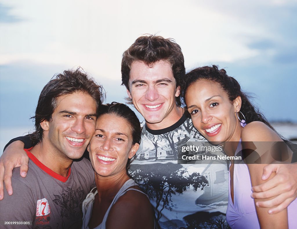 Two young couples smiling, arms around each other, portrait