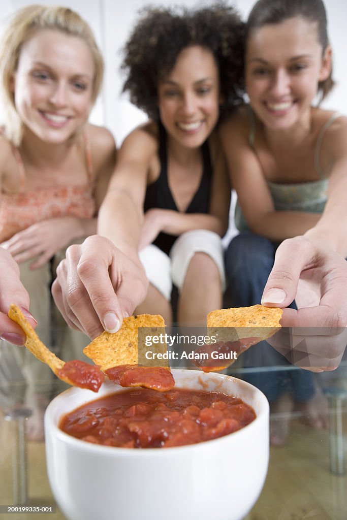 Three friends eating tortillas with dip (focus on tortillas and dip)