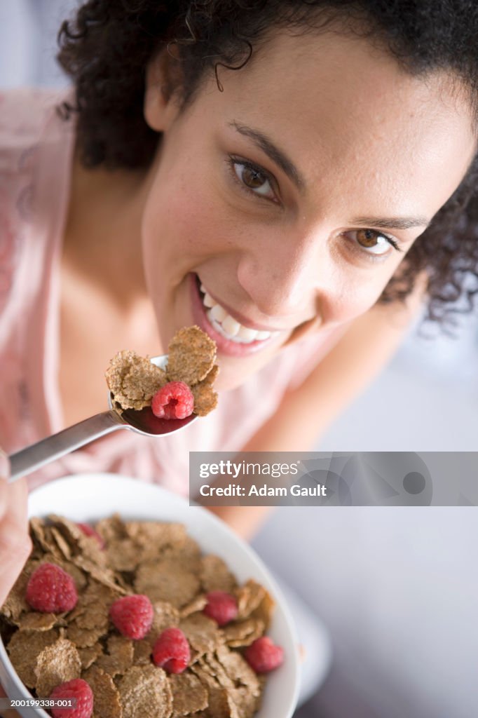 Woman eating bowl of cereal, smiling, portrait, close-up