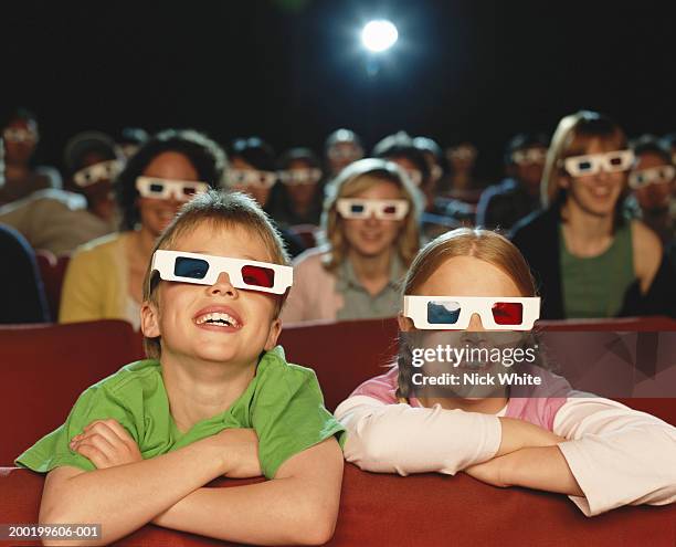 boy and girl (8-10) in cinema watching 3-d movie, smiling - kinosaal stock-fotos und bilder