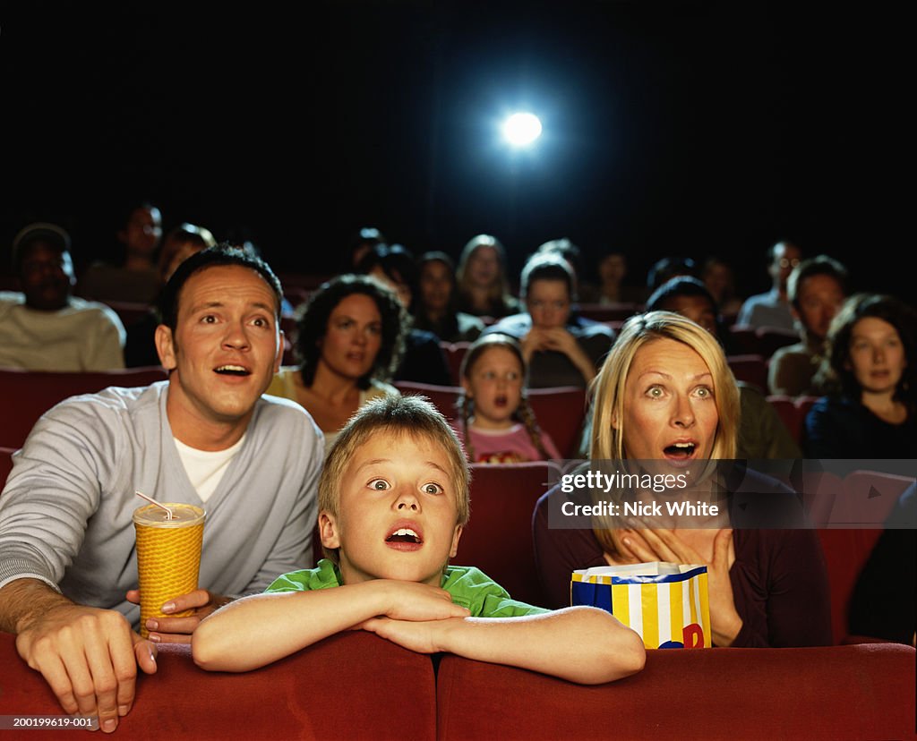 Parents and son (9-11) in cinema reacting to film, close-up