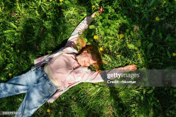 sunny serenity - girl lounging on park grass, enjoying sunshine - sunbathing stock pictures, royalty-free photos & images