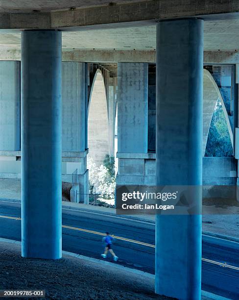 man jogging under elevated roadway, side view (blurred motion) - pasadena california stock-fotos und bilder
