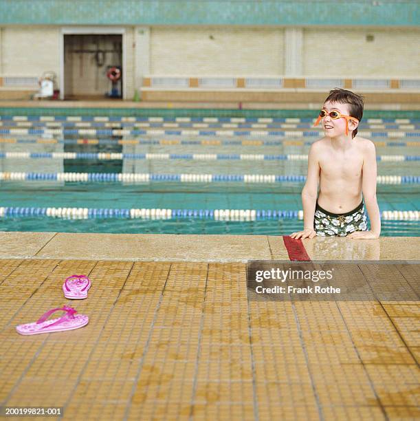 boy (7-9) wearing goggles, pulling self out of pool - badelatsche stock-fotos und bilder